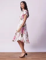 Vestido blanco con estampado floral en tonos rosados, violetas y verdes. Escote en V tanto en la parte delantera como en la espalda. Cintura elastizada con punto smock y forro interno a tono.