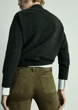 Pantalón de jean verde militar, de tiro medio, corte acampanado y largo cropped. Presenta bolsillos de parche delanteros y traseros, trabillas y terminación desflecada.
