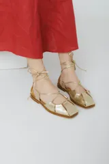 Sandalias chatitas de cuero color bordó, con puntera cuadrada y tiras finas que se atan al tobillo.