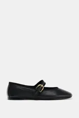 Zapato plano tipo bailarina de cuero negro, con tira sobre el empeine y hebilla metálica dorada ajustable.