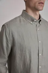 Camisa blanca de lino con cuello abotonado, manga larga con puños abotonados y corte clásico.