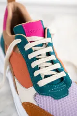Zapatillas deportivas con paneles de cuero, gamuza y malla en colores naranja, marrón, verde, lila y crema. Cordones gruesos multicolor y suela chunky blanca.