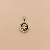 Dije redondo en plata 925 y oro con centro de ónix negro y diseño de trébol de cuatro hojas dorado.