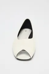 Zapato plano tipo bailarina de piel color crema con efecto craquelado y punta cuadrada abierta.