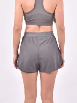 Short deportivo negro de doble capa, con una capa exterior suelta y una capa interior ajustada tipo calza. Presenta un detalle vertical blanco en el lateral derecho.