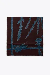 Pañuelo rectangular de lana color marrón con estampado abstracto en azul. Tiene terminaciones deshilachadas.