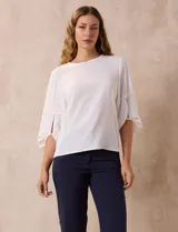 Blusa de gasa color blanco con estampado de hojas verdes, de mangas 3/4 abullonadas con puños elásticos.