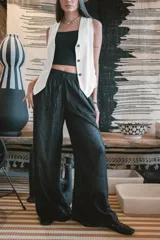 Chaleco negro de vestir, con escote en V y cierre frontal de botones dorados.