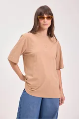 Remera color tostado de algodón con cuello redondo y mangas cortas. Estampado pequeño en el centro del pecho con un sol y texto.