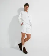Camisa blanca de manga larga, confeccionada en terciopelo con cuello clásico y bolsillos frontales.