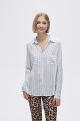 Camisa a rayas verticales grises y blancas, con cuello camisero, cierre frontal con botones, mangas largas con trabillas para enrollar y dos bolsillos de parche en el pecho.