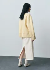 Buzo oversize color amarillo pastel, de manga larga y cuello redondo.