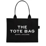 Bolso tote negro de lona con asas superiores y estampado frontal con la leyenda "THE TOTE BAG MARC JACOBS" en color blanco.