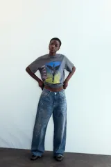 Camiseta de algodón gris oscuro con efecto lavado, corte oversize y manga corta. Presenta un estampado frontal con la ilustración del álbum "In Utero" de Nirvana, con la palabra "NIRVANA" en vertical a la izquierda y "IN UTERO" a la derecha.