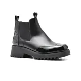 Bota Chelsea de cuero sintético negro con elástico lateral, puntera y talón charolados, plataforma track y tiradores en la caña.