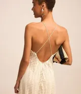 Vestido midi color crema con textura de agujeritos, escote halter, breteles finos cruzados en la espalda y forro interior.
