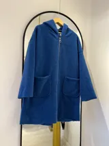 Tapado largo azul francia con capucha integrada, cierre frontal con cremallera y bolsillos delanteros.