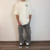 Pantalón jean color beige, de corte holgado y estilo cargo, con múltiples bolsillos laterales.