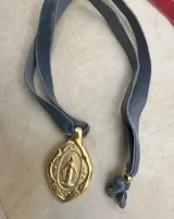 Collar con dije ovalado dorado con la imagen de la Virgen Milagrosa y cinta de terciopelo celeste.