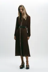 Vestido midi marrón chocolate plisado, con cuello solapa, manga larga y cinturón. Presenta cierre frontal con botones y vivos blancos a contraste en cuello, mangas y botonera. Incluye forro interior.