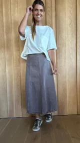 Pollera midi de denim color gris con corte en A y costuras verticales al frente.
