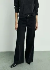 Pantalón de jean negro de corte wide leg, con tiro alto, bolsillos frontales de parche y cierre frontal con cremallera y botón.