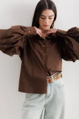 Camisa color beige de algodón con mangas abullonadas y cierre con botones.