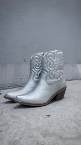 Bota corta plateada de estilo texano con bordados en el caño, taco de madera y cierre lateral.