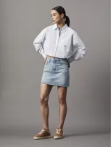 Camisa cropped de popelina de algodón suave a rayas verticales celestes y blancas, de corte relaxed, con cuello en punta, puños segados, bajo redondeado y bolsillo en el pecho con insignia con el logo de Calvin Klein.