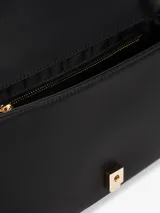 Cartera tipo clutch Tommy Hilfiger de poliuretano negro con diseño acolchado, insignia del monograma TH dorada en el frente, cierre de solapa magnético, correa de hombro y bolsillo interior con cremallera.