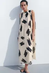 Vestido midi de Zara Woman Collection confeccionado en hilatura de viscosa color crudo con estampado abstracto en negro. Tiene cuello redondo, manga sisa, tejido plisado, forro interior y cierre en la espalda.