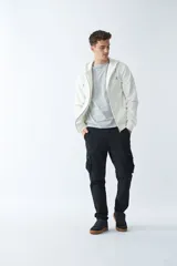 Campera de felpa color beige con cierre frontal, capucha con cordón ajustable, bolsillos laterales y logo estampado en el pecho.