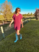 Vestido corto fucsia tejido en lurex metálico con escote en V y mangas cortas.