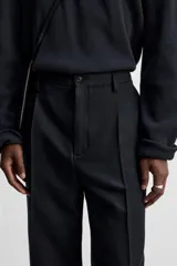 Pantalón de vestir negro de corte recto, con cintura elástica, pliegues frontales, bolsillos laterales y traseros.