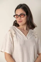 Blusa italiana color crudo de lino con escote en V y mangas cortas. Presenta detalle de bordado calado en el canesú.