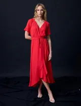Vestido largo de gasa color rojo, con escote en V, mangas cortas con volados, cintura elastizada con lazo de ajuste y ruedo asimétrico con volados. Tiene forro interno a tono.