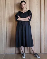 Vestido midi celeste de denim, con escote con lazo, mangas 3/4 abullonadas y corte evasé.