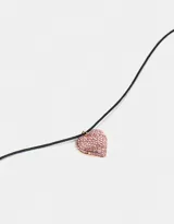 Gargantilla choker de cordón negro con dije de corazón dorado cubierto de strass rosas.