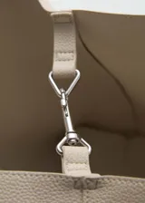 Bolso tipo tote de color beige con textura símil cuero, doble asa corta y cierre de gancho.