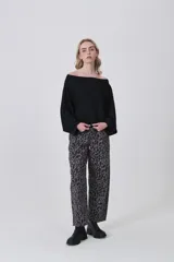 Sweater holgado de tejido ligero, color beige claro, con escote asimétrico que deja un hombro al descubierto.