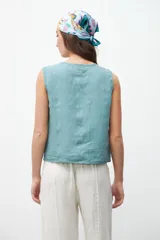 Chaleco color celeste con textura, corte recto, sin mangas y abotonado al frente.