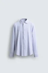 Camisa celeste a rayas verticales blancas, de corte recto, con cuello italiano abierto, mangas largas con puños abotonados y cierre frontal con botones.