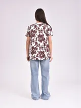 Remera estampada con motivos florales en tonos naranja, beige, gris y rosa.
