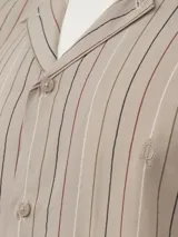 Camisa de manga corta azul marino con rayas verticales blancas, amarillas y marrones, con cuello cubano y cierre con botones.