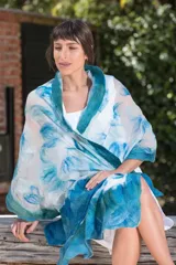 Echarpe blanca de gasa de seda natural con lana Merino superfina en tonos azules y turquesas, con volados en los extremos.