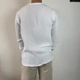 Camisa blanca de muselina con cuello mao y manga larga con puños abotonados.