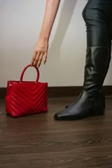 Bota de caña alta de cuero color rojo, con cierre lateral y taco cuadrado de 4 cm.