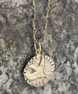 Collar con cadena de eslabones plateados y dije redondo con la figura del Espíritu Santo.