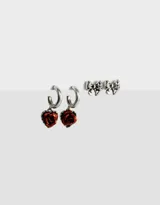 Set de dos pares de aros plateados: un par de argollas con dije de rosa roja y un par de aros tipo botón con forma de moño.