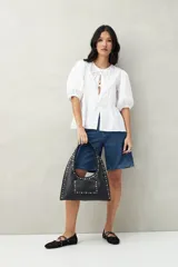 Blusa blanca de algodón con mangas abullonadas, escote redondo y lazos frontales.